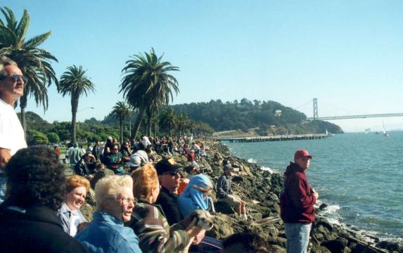 An expectant crowd line the shore of Treasure Island
